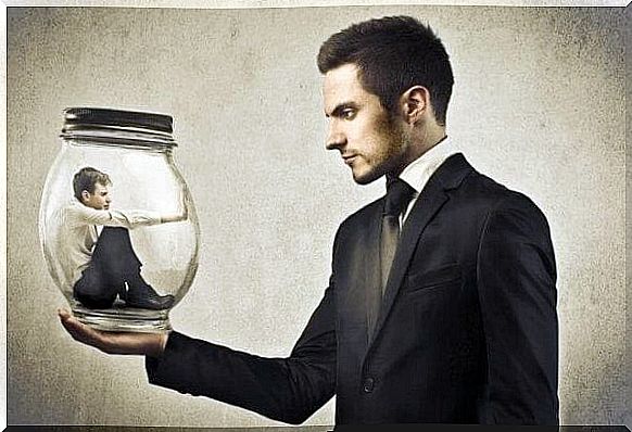 Man holds glass jar with another man in it