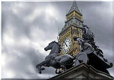 A statue with horses and parliament in London in the background 