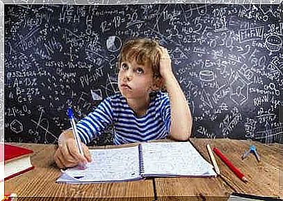 A boy is sitting at a desk with a writing pad and a pen