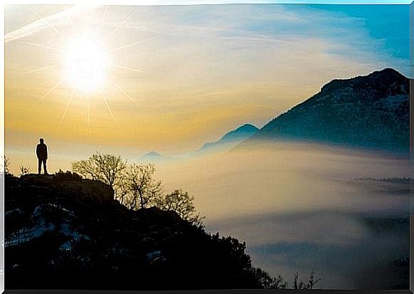 Man stands alone on a mountain and practices mindfulness