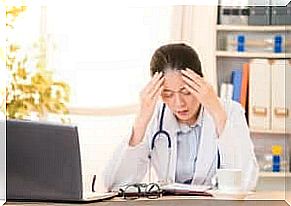 A woman in a doctor's uniform holds her hands to her head