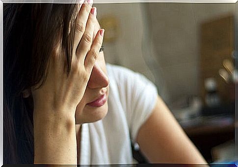 Woman holds her hand to her head because she suffers from headache